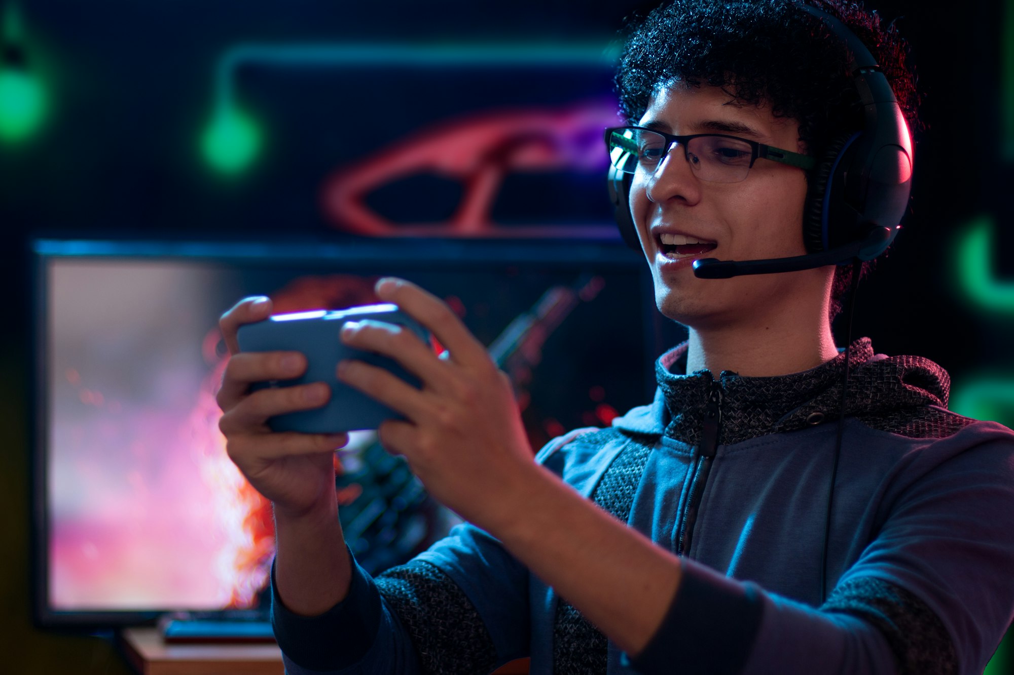 A young Latino adult immersed and happy in a mobile gaming experience with a headset